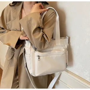 Beige multi-pocket nylon tote bag styled with a trench coat for commuting fashion