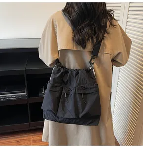 Detail of black nylon tote bag featuring functional cargo pockets and drawstring closure