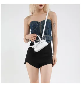Mini sac à bandoulière en cuir blanc avec boucles argentées et détails cloutés sur mannequin