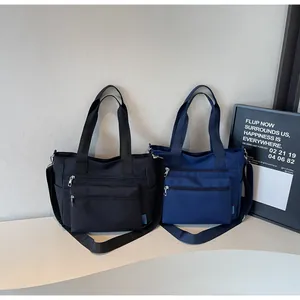 Detail of multi-zippered nylon tote bags in black and navy with adjustable straps