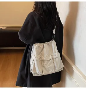 Close-up of lightweight light gray nylon crossbody bag with drawstring and dual front pockets