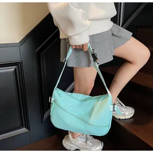 Detail of mint green nylon messenger bag featuring adjustable buckle strap and zip pocket