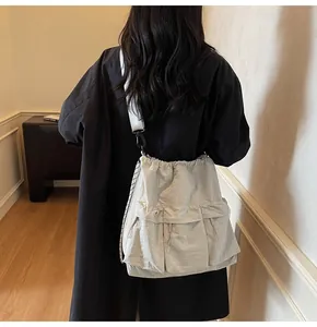 Detail of grey nylon tote bag showing drawstring closure and large front functional pockets