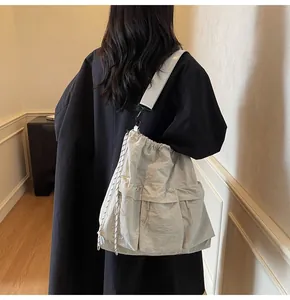 Close-up of a light grey nylon tote bag showing drawstring closure and cargo pockets