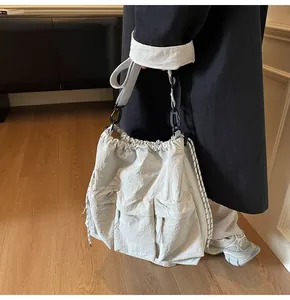 Detail of light grey nylon tote bag with drawstring closure and heavy-duty rope straps