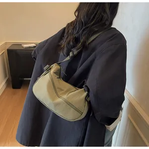 Detail view of the lightweight olive green nylon crescent crossbody bag worn by a model