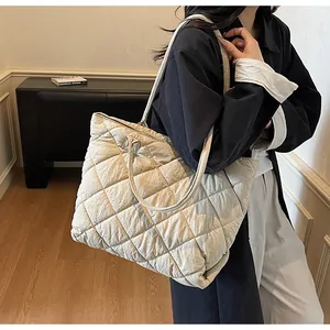Detail of beige quilted puffer tote bag showing texture and dual strap versatility