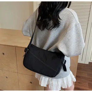 Detail showing the adjustable wide strap and side view of the black nylon crossbody bag