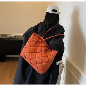 Detailed back view of a large caramel quilted tote bag worn over a navy coat for commuting