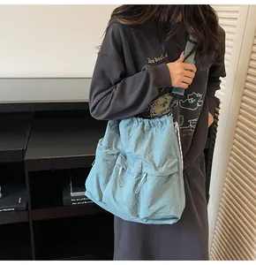 Detail of light blue nylon tote bag with drawstring closure and functional front zip pockets