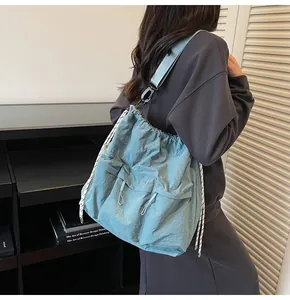 Detail of grey-blue nylon tote bag with drawstring pockets and woven shoulder strap