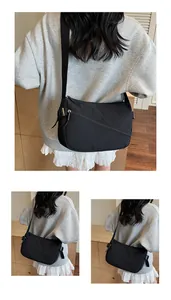 Detail of minimalist black nylon crossbody bag featuring adjustable fabric shoulder strap