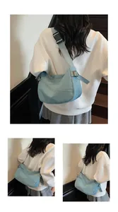 Detail of light blue crescent crossbody bag featuring micro-wrinkle nylon texture and strap