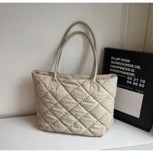 Detail of minimalist quilted tote bag showing beige rhombic stitching and soft fabric