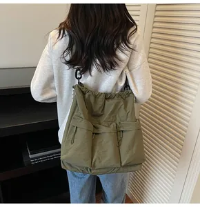 Rear view of model wearing an army green nylon drawstring tote bag with utility pockets