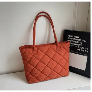 Detail of diamond quilted tote bag in dark orange with double handles and side gusset