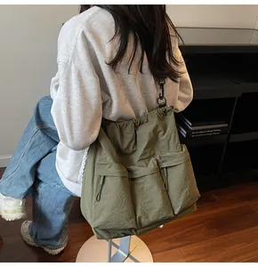 Detail of army green nylon tote bag featuring three front pockets and drawstring closure