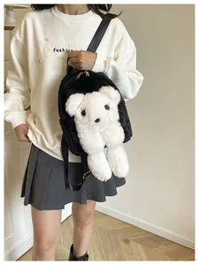 Detail of plush black backpack featuring a white teddy bear doll and golden metal zipper