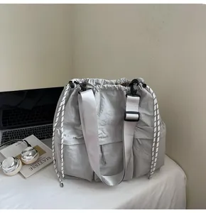 Detail of light grey nylon drawstring tote bag with褶皱 texture and adjustable wide strap