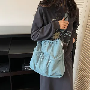 Light blue large nylon tote bag with drawstring pockets shown on a model for travel