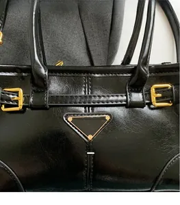 Close-up of black glossy crinkled leather with gold metal buckle and triangle hardware