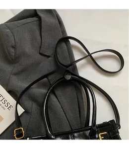 Detail of smooth black leather shoulder strap with gold metal buckle on a handbag