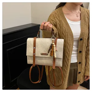 Détail d'un sac à dos en cuir vintage avec pendentif en perles et logo de marque gravé
