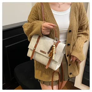 Gros plan sur un sac messager vintage avec perles en bois et logo métallique