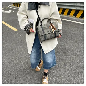 Détail d'un sac messager vintage gris avec lanières en cuir et perles décoratives en bois