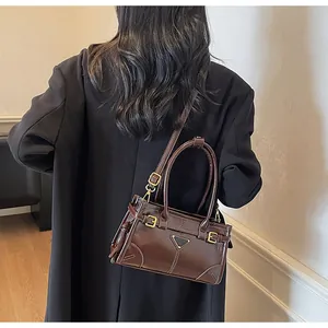 Detail of a dark brown glossy vintage handbag featuring gold buckles and shoulder strap