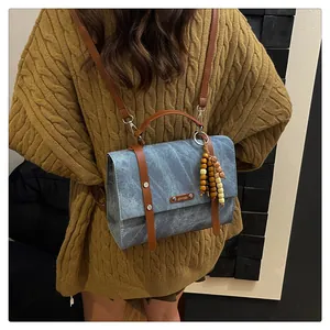 Vue détaillée d'un sac à dos vintage bleu texturé avec lanières en cuir brun et perles