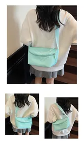 Detail of mint green nylon crossbody bag showing textured fabric and zip compartments