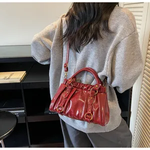 Détail d'un sac à main plissé bordeaux avec ferrures dorées dans un décor de style de vie