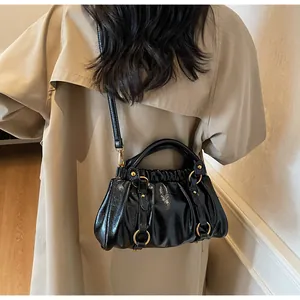 Détail du sac plissé en cuir brillant noir porté avec un trench-coat beige