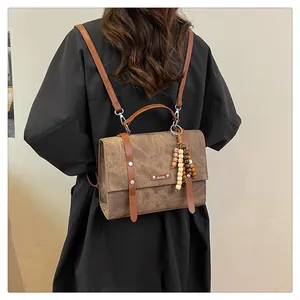 Détail du sac à dos vintage marron avec pendentif en perles de bois sur mannequin