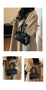 Detail view of glossy black handbag with gold triangle logo and crossbody strap