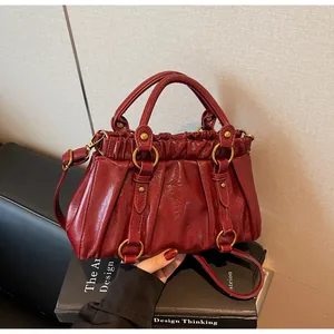 Détail de la texture plissée et du cuir brillant rouge vin sur le sac à bandoulière