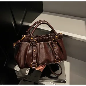 Détails d'un sac plissé marron foncé avec anneaux métalliques vintage et rivets dorés