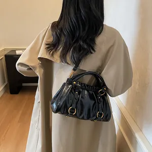 Sac chic en cuir plissé noir avec détails dorés porté à l'épaule par un modèle