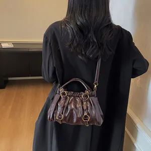 Sac bandoulière plissé marron foncé avec détails dorés et finition brillante