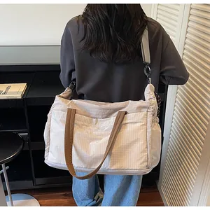 Detail of expandable nylon travel bag with drawstring sides and adjustable shoulder strap