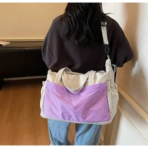 Detail of expandable travel bag with purple plaid pocket and adjustable strap
