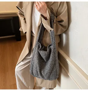 Detail of grey wool-like texture tote bag worn by a model in a camel coat