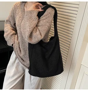 Detail of black textured wool tote bag showing thick granular fabric and shoulder strap