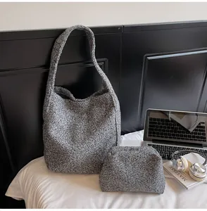 Close-up of grey textured wool tote bag set with matching inner pouch on white surface