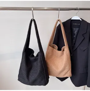 Detail view of plush fleece tote bags in black and camel hanging with a chic blazer