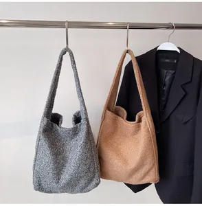 Detail of wool-like tote bags in grey and camel hanging with a black suit blazer