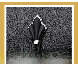Détail du fermoir en métal argenté sur un sac bandoulière noir en cuir grainé