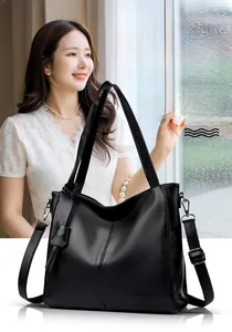Close-up of black cowhide leather tote bag showing lychee grain texture and brand logo