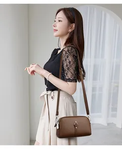 Détail du sac en cuir marron à motif litchi avec décor métallique sur un mannequin